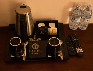 a table with a tea pot and two mugs and remote controls at Tales Luxury in Kampala
