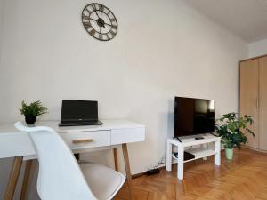 a white desk with a laptop and a clock on a wall at Home4You Szombathely in Szombathely