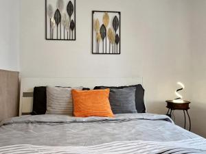 a bedroom with a bed with an orange pillow at Home4You Szombathely in Szombathely