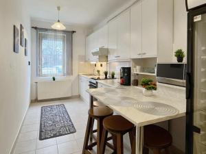 a kitchen with white cabinets and a island with bar stools at Home4You Szombathely in Szombathely +5 photos