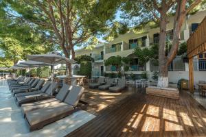 een terras met ligstoelen en parasols voor een hotel bij Contessa Hotel in Argassi
