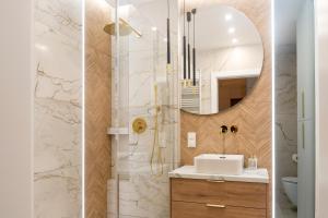 a bathroom with a shower with a sink and a mirror at Apartament Zakrzówek - Chilloway in Krakow