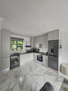 a kitchen with white cabinets and a washer and dryer at Tash's Place in Roodepoort