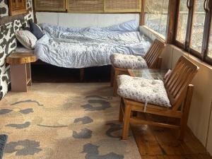 a room with a bed and two chairs and a glass table at The Himalayan Home in Nagar +7 photos