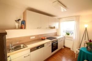 a kitchen with white cabinets and a sink and a window at HäuslmaierS Urlaubswohnung in Siegsdorf