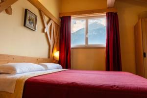a bedroom with a bed with red curtains and a window at Hotel Continental in Andalo