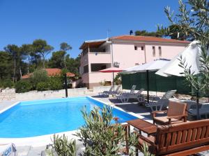 a swimming pool with chairs and umbrellas next to a house at VILLA DARIA in Pakoštane