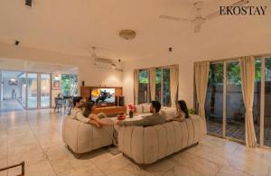 a group of people sitting on couches in a living room at EKOSTAY Gold - AshBee Villa in Kīhīm