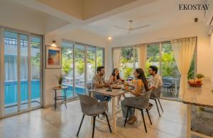 a group of people sitting at a table in a house at EKOSTAY Gold - AshBee Villa in Kīhīm