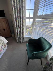 een slaapkamer met een groene stoel en een raam bij Bay View Guest House in Beer