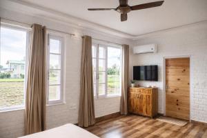 a bedroom with a bed and a tv and windows at Hibiscus in Kota Bāgh