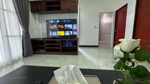 a living room with a television and a table with a flower at Soulful Stay Phuket -Distant Seaview and Mountain View Retreat, Patong in Patong Beach