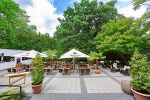 un patio esterno con tavoli, sedie e ombrelloni di Dorint Kongresshotel Düsseldorf/Neuss a Neuss