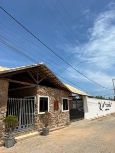 a stone building with a fence next to a street at Chalé em Condomínio com in Aracati