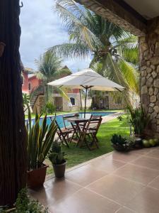 a patio with a table and umbrella next to a pool at Chalé em Condomínio com in Aracati +24 photos