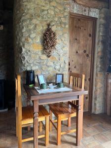 a wooden table with two chairs and a stone wall at Divina Reserva- Cabana Maçanilha in Bom Retiro