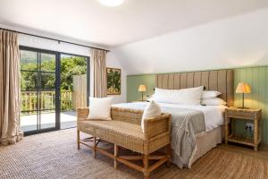 a bedroom with a bed and a chair and a window at Noordhoek Village Hotel in Noordhoek +93 photos