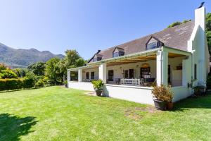 a house with a large yard with mountains in the background at Noordhoek Village Hotel in Noordhoek