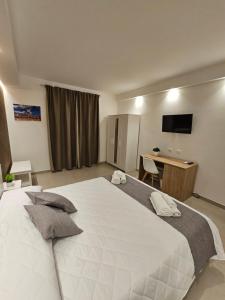 een slaapkamer met een groot wit bed en een bureau bij Aura B&B in Pachino