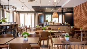 a restaurant with tables and chairs and a brick wall at Campanile Brive-La-Gaillarde Ouest in Brive-la-Gaillarde