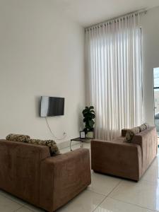 a living room with two brown couches and a tv at Espaço verão in Santa Fé do Sul