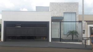 a white building with a palm tree in front of it at Espaço verão in Santa Fé do Sul
