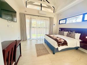 a bedroom with a bed and a flat screen tv at 19 On Bay Noakes in Harare