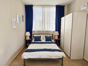 a bedroom with a bed with blue curtains and a window at Beachfront Bliss 3 bedroom Privacy in Netanya