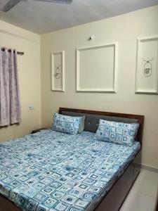a bed with blue and white pillows in a room at Sunset stay in Daman