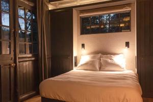 a bed in a room with two windows at Neska Lodge in Saint-Rémy-lʼHonoré
