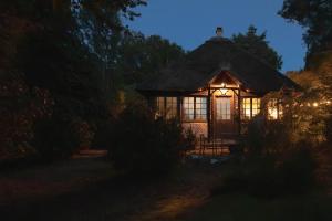 a small cabin with a thatched roof at night at Neska Lodge in Saint-Rémy-lʼHonoré +12 photos