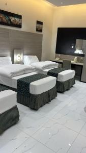 a hotel room with two beds and a flat screen tv at فندق ثرا الرواد in Abu Arish +12 photos