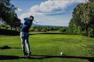 a man swinging a golf club on a golf course at Lake Suite in Trevignano Romano