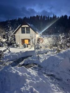 una casa è coperta di neve con le luci accese di Chalet Mignon - Aproka adorable small guest house a Sicasău