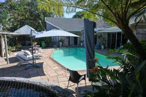 a swimming pool with two chairs and an umbrella at Matts Rest Bnb & Self-catering in Pietermaritzburg
