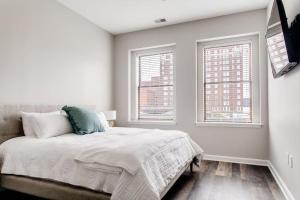 a white bedroom with a bed and two windows at Historic Elegance Modern Amenities Gym in Louisville