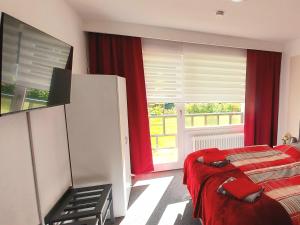 een slaapkamer met een bed en een raam met rode gordijnen bij Hotel Georgenhöhe Wildemann in Wildemann +10 foto's