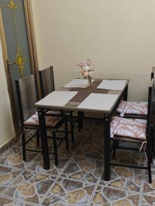 a wooden table with two chairs and a vase of flowers on it at TATAICHA Appart in NʼDjamena