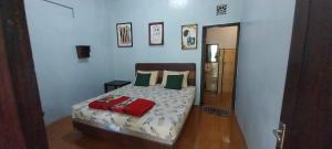 a bedroom with a bed with green and red pillows at Hadi Homestay Garden View in Jambu