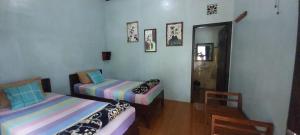 a room with two beds and a table and a chair at Hadi Homestay Garden View in Jambu