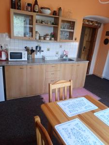 a kitchen with a wooden table and a sink at Apartmány Somora in Doksy