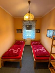 a bedroom with two beds and a window and a chandelier at Apartmány Somora in Doksy