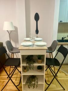 a table with plates and glasses and plants on it at Tik-tak apartment in Petrovaradin
