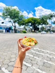 a person holding a bowl of food in a street at Hotel Dairy Walley in Itapetinga
