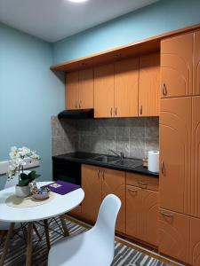 a kitchen with wooden cabinets and a white table and chairs at IWA CENTAR Apartments & Wellness in Vrnjačka Banja