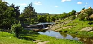 a river with a bridge in the middle of a field at La Maguada in Tanti +8 photos