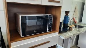 a microwave on a shelf in a kitchen at Flat Terras de Portinari in Barretos