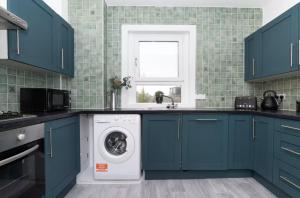 una cucina con armadi blu e lavatrice di Free Parking - Central - Dunfermline Sleeps 4 a Dunfermline