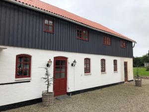 a white and red barn with red doors and a tree at Als Kloster in Sønderborg