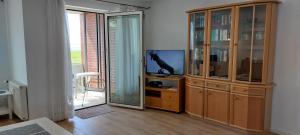 a living room with a entertainment center with a tv at Exklusive Ferienwohnung am Südstrand mit Wintergarten & Hafenblick Wohnung 113 in Wilhelmshaven